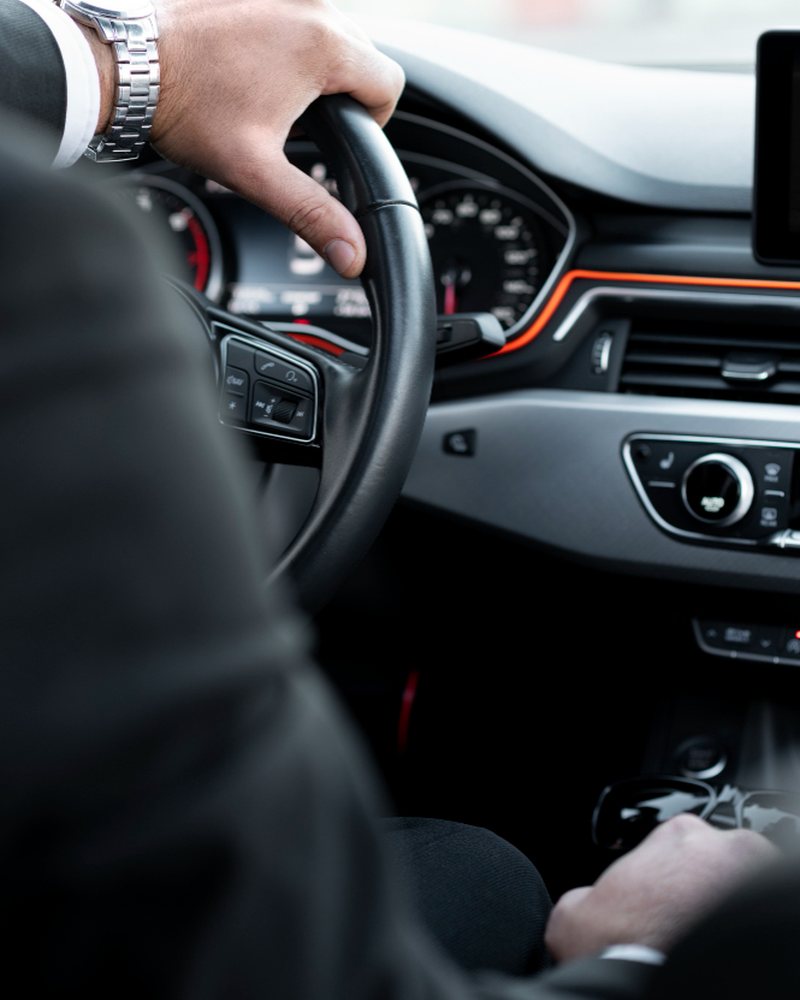 Chauffeur's hands on the steering wheel of a premium vehicle